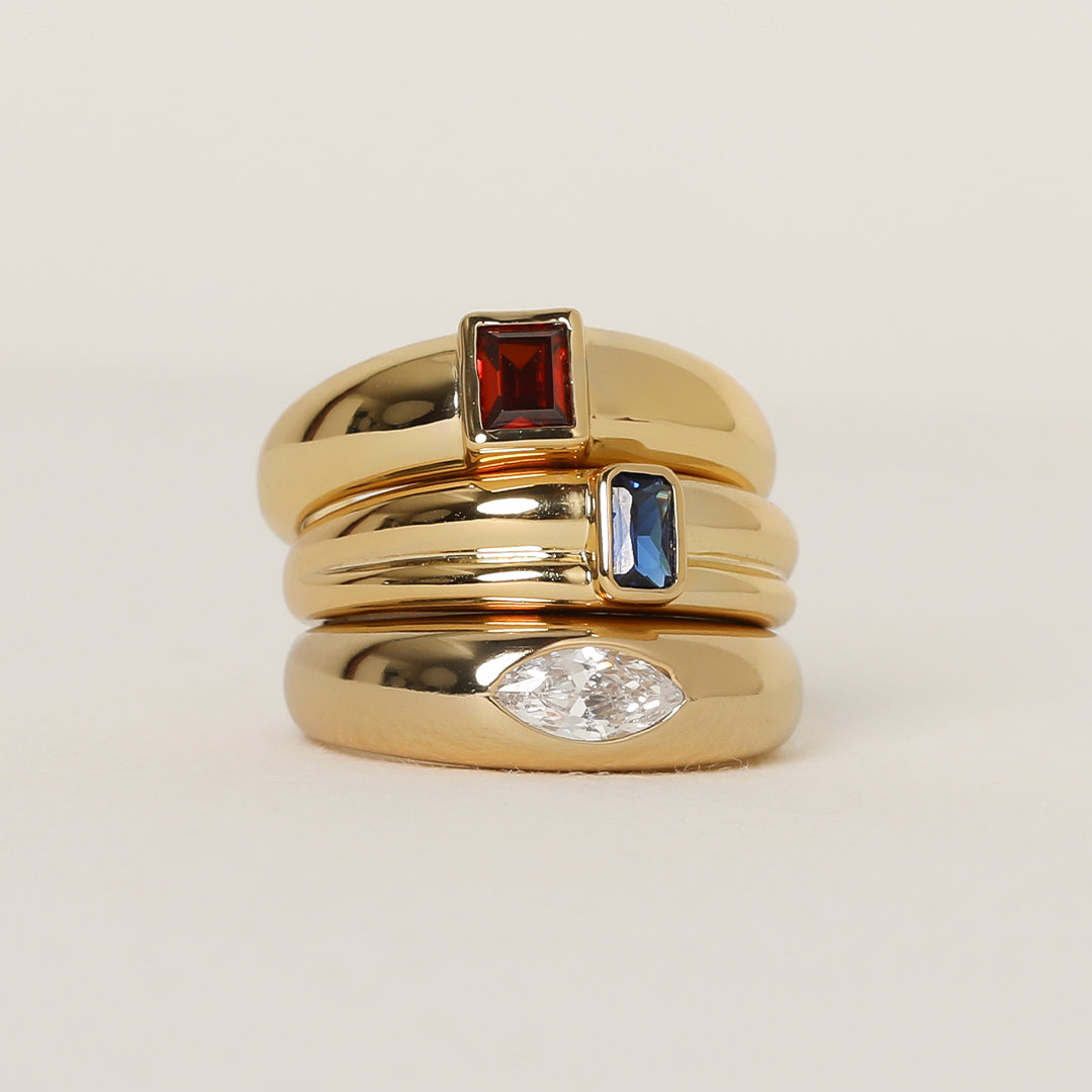 gold ring inspired by the city of love with a deep red square cubic zirconia bezel set stacked on two gold rings on white background