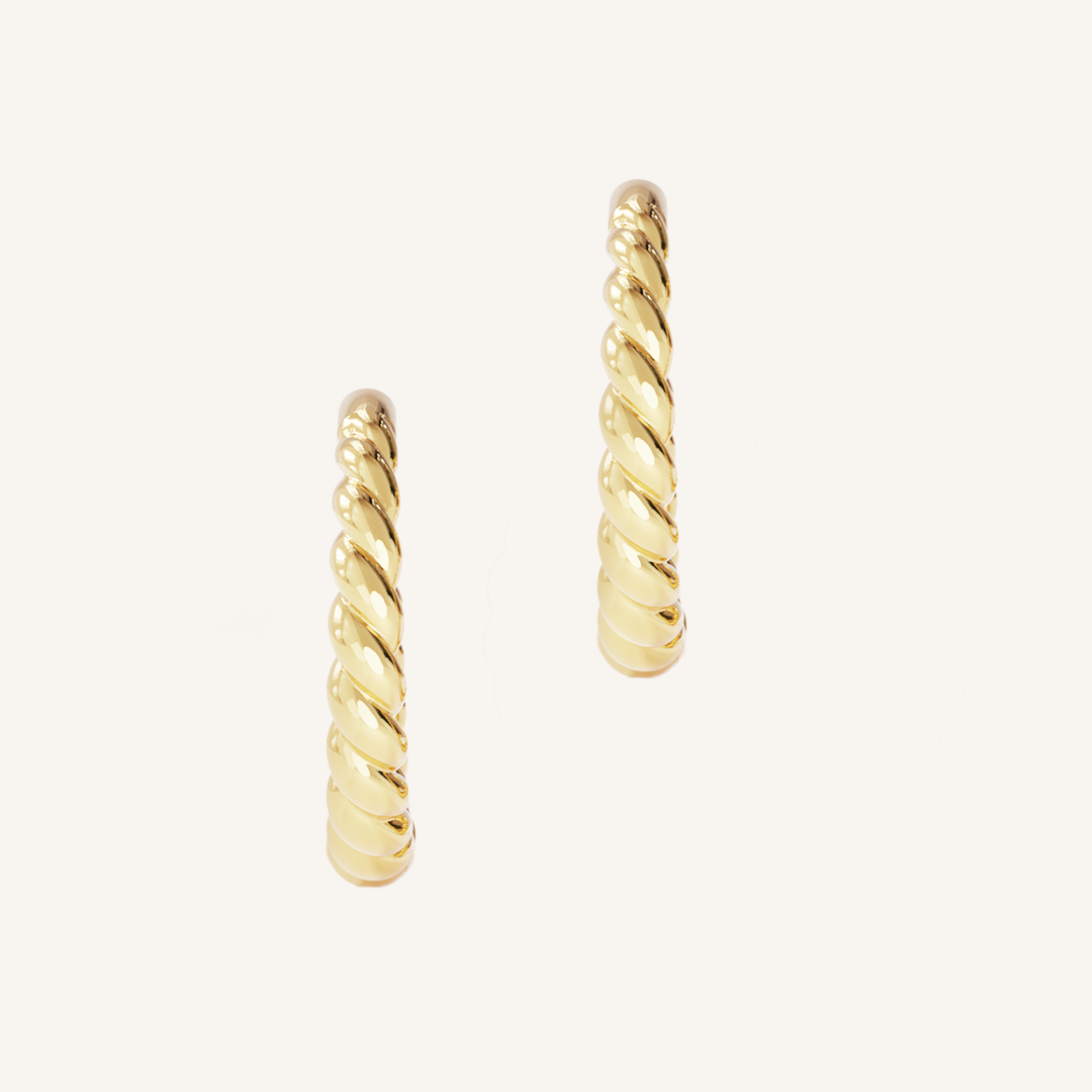 gold hoops inspired by intricate details of the Eiffel tower on white background