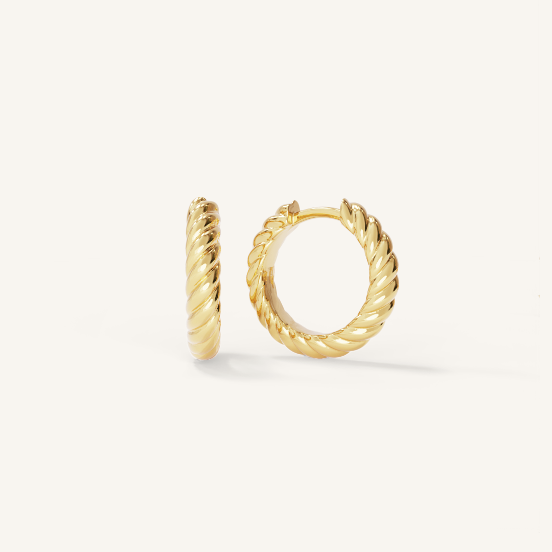 gold delicate hoops with a twist design on white background 
