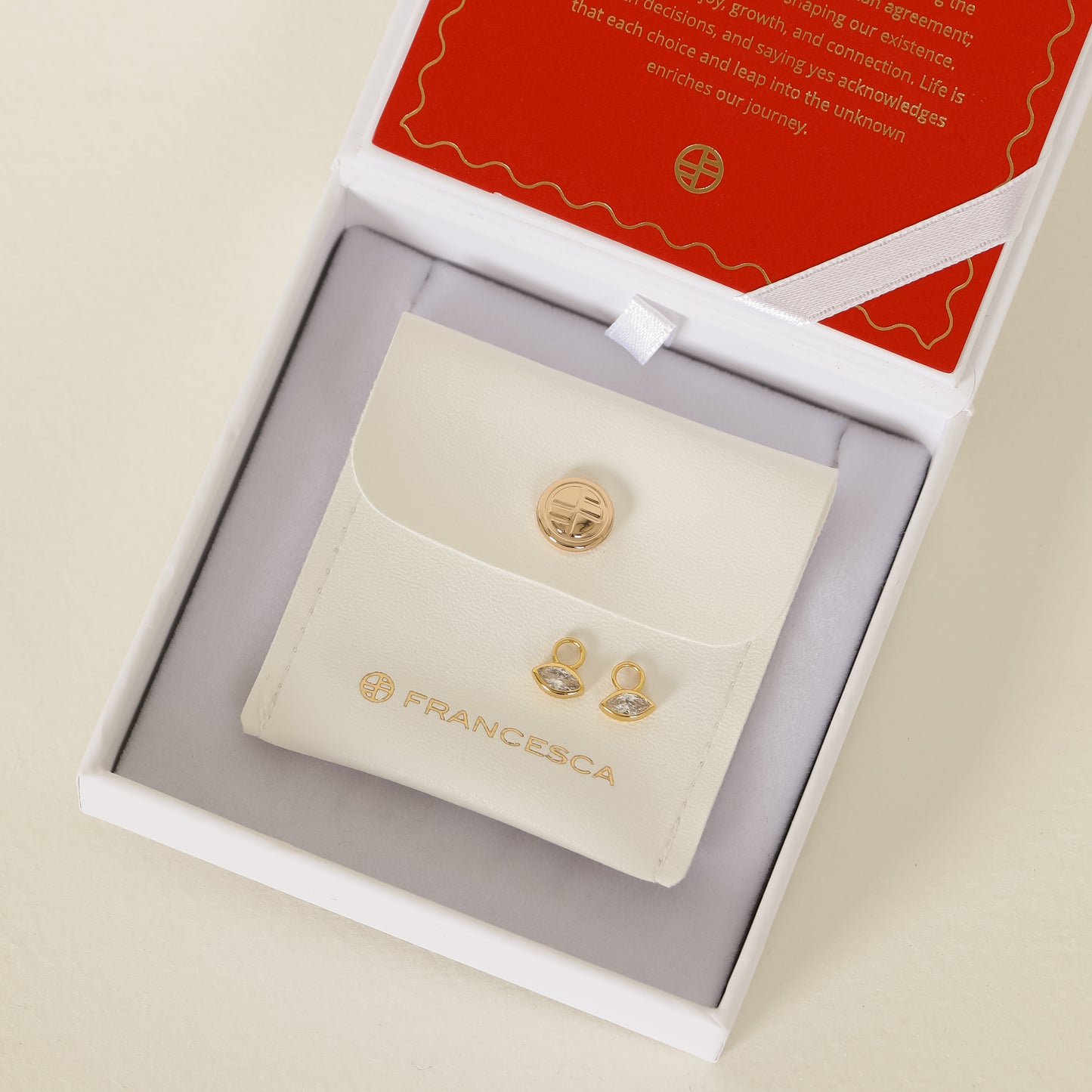 gold hoop charms inspired by the Louvre's architecture with Marquise cut white cubic zirconia bezel set on white box