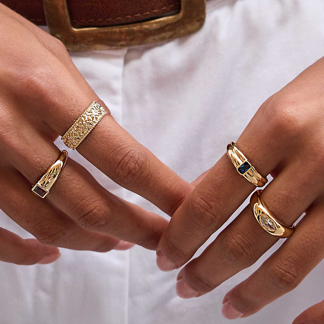 intricately designed statement gold ring inspired by Paris close up on fingers with other rings in the Oui Collection 