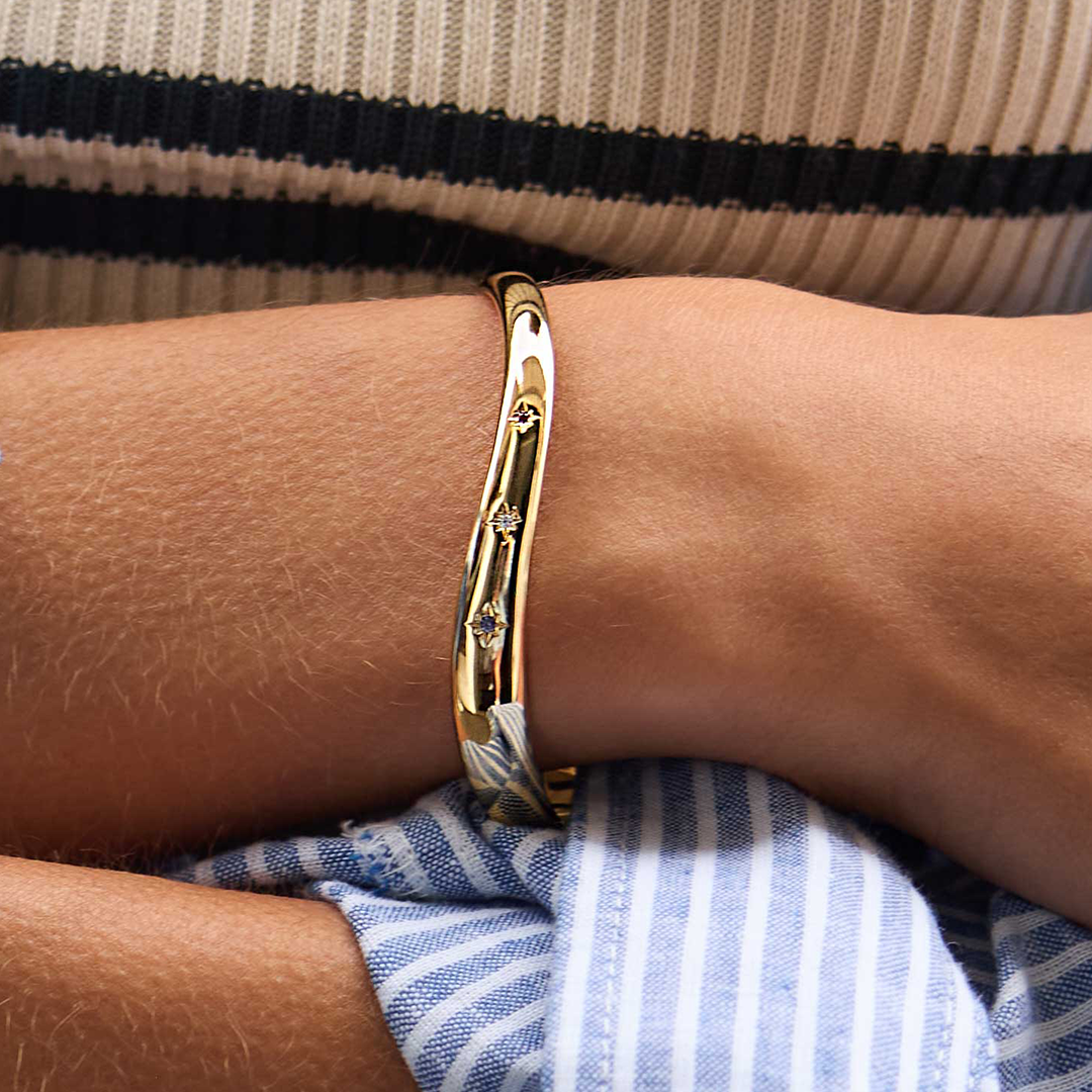 gold asymmetrical cuff with red, white and blue cubic zirconias close up on wrist 