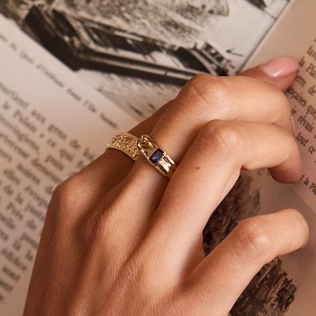  gold ring with navy blue cubic zirconia  close up on finger