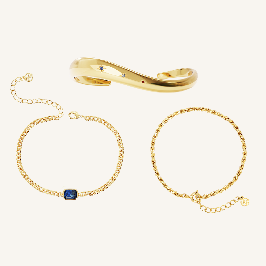 gold chain bracelet with a navy blue cubic zirconia asymmetrical cuff and rope bracelet set on white background 