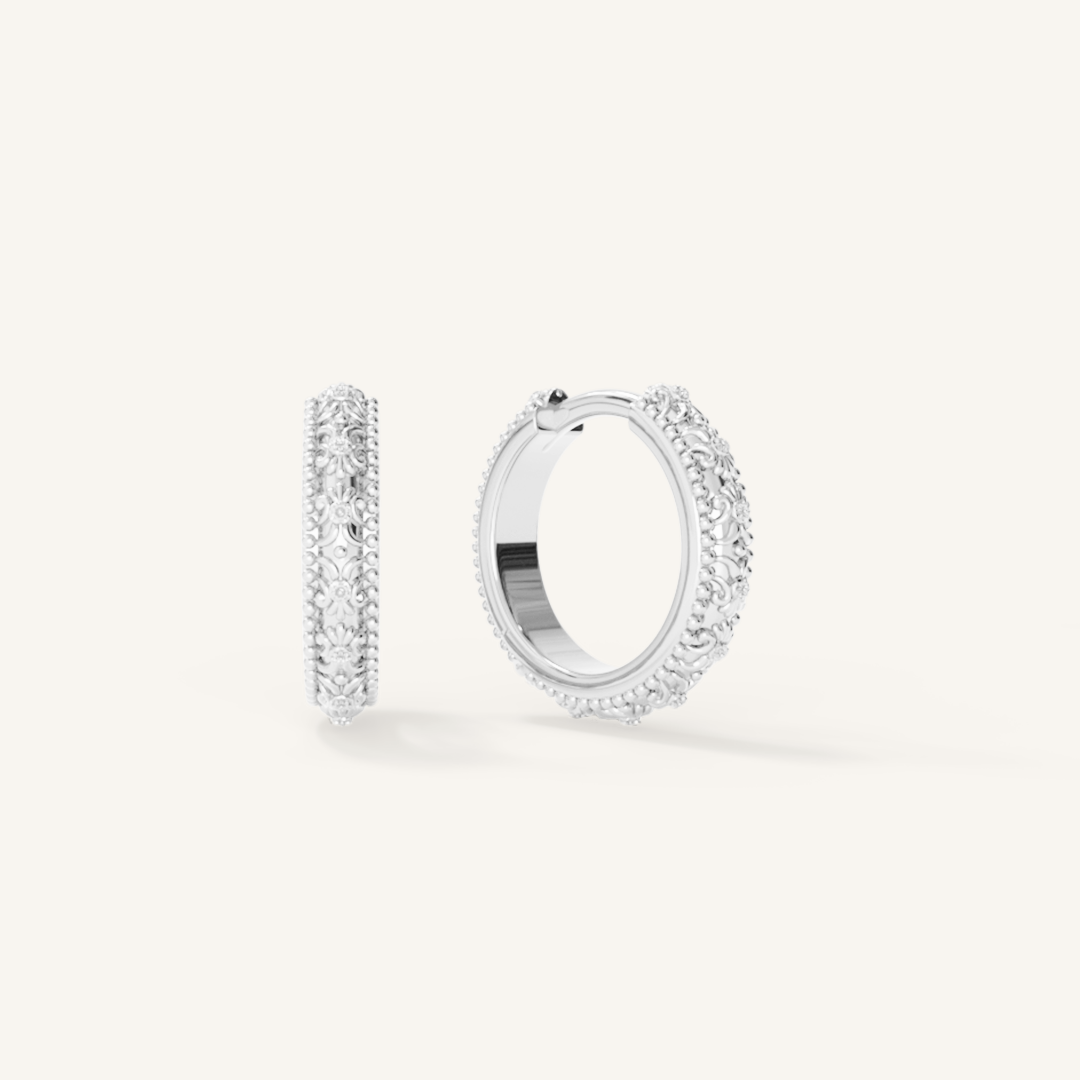 intricately designed silver hoops on white background