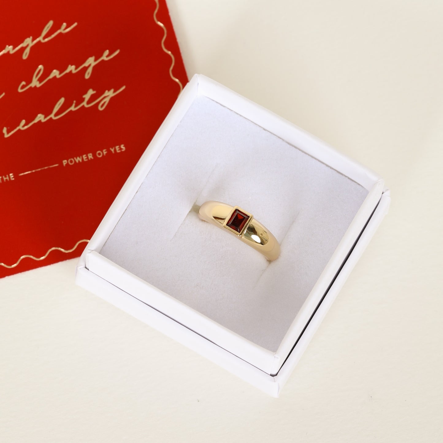 gold ring inspired by the city of love with a deep red square cubic zirconia bezel set on white ring box