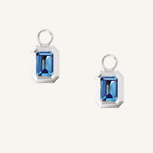 rectangular silver hoop charms with Blue emerald cut cubic zirconias bezel set on white background 