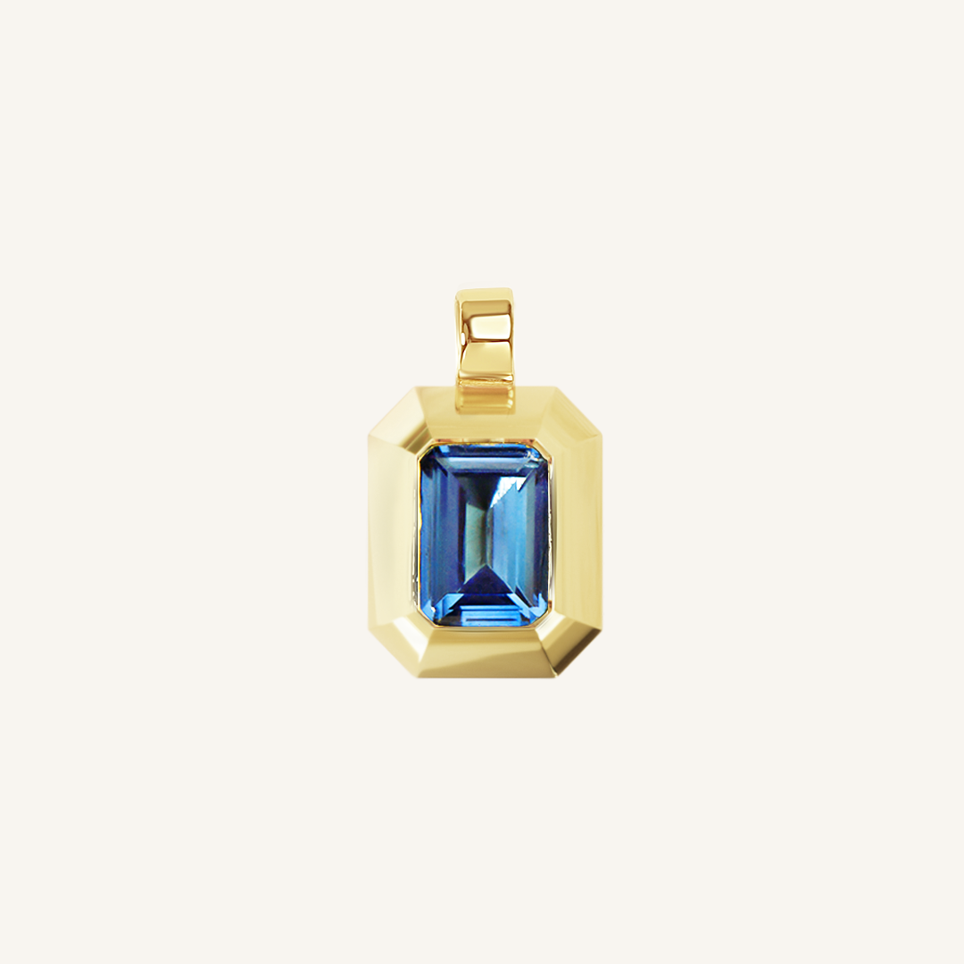 Gold charm with Blue emerald cut cubic zirconia bezel set Inspired by the halls of Versailles on white background 