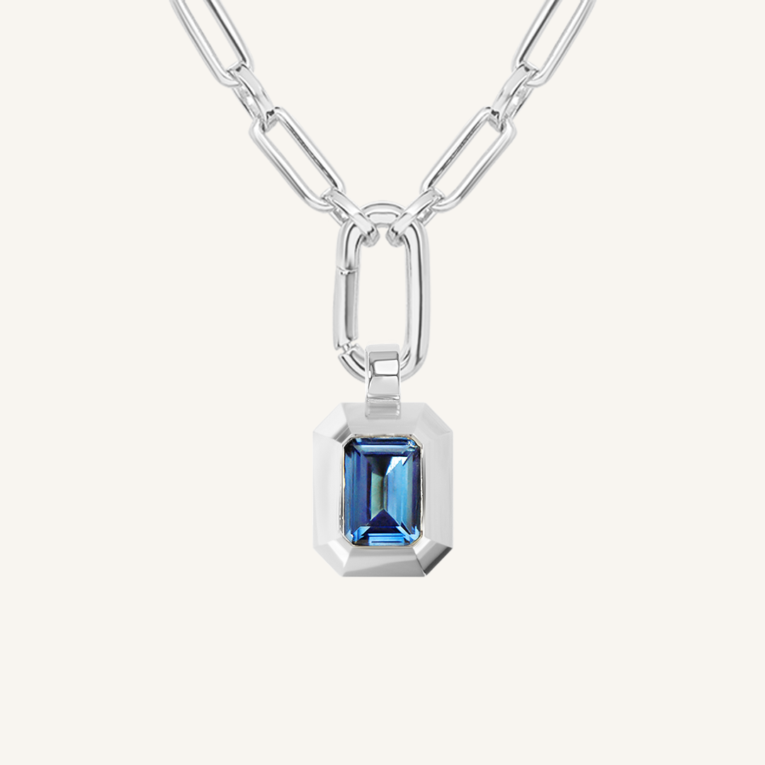 silver charm with Blue emerald cut cubic zirconia bezel set Inspired by the halls of Versailles on link chain on white background 