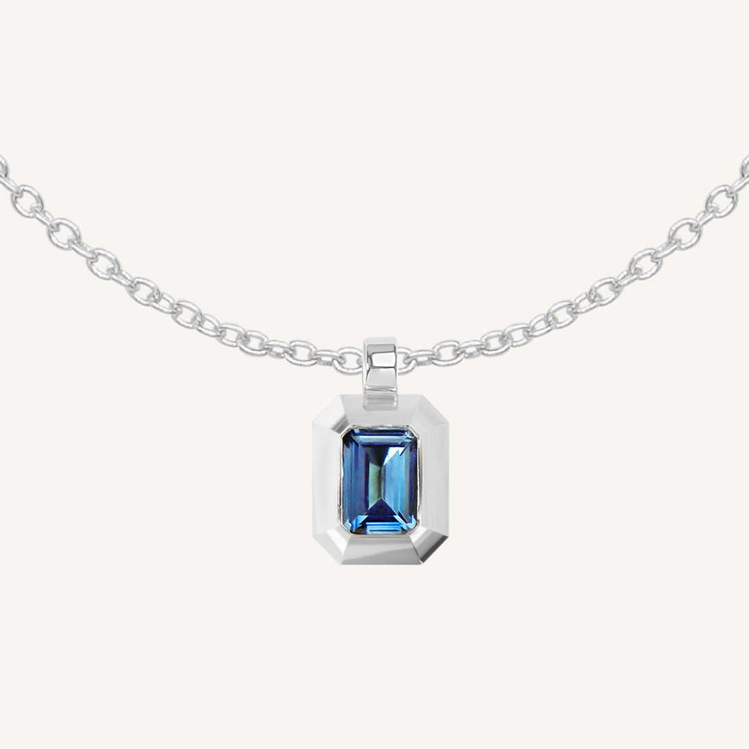 silver charm with Blue emerald cut cubic zirconia bezel set Inspired by the halls of Versailles on plain chain on white background 