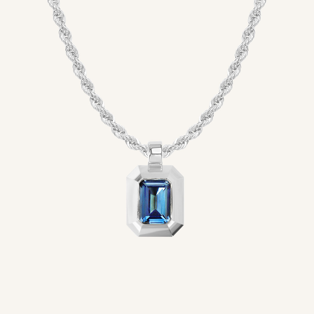 silver charm with Blue emerald cut cubic zirconia bezel set Inspired by the halls of Versailles on rope chain on white background 