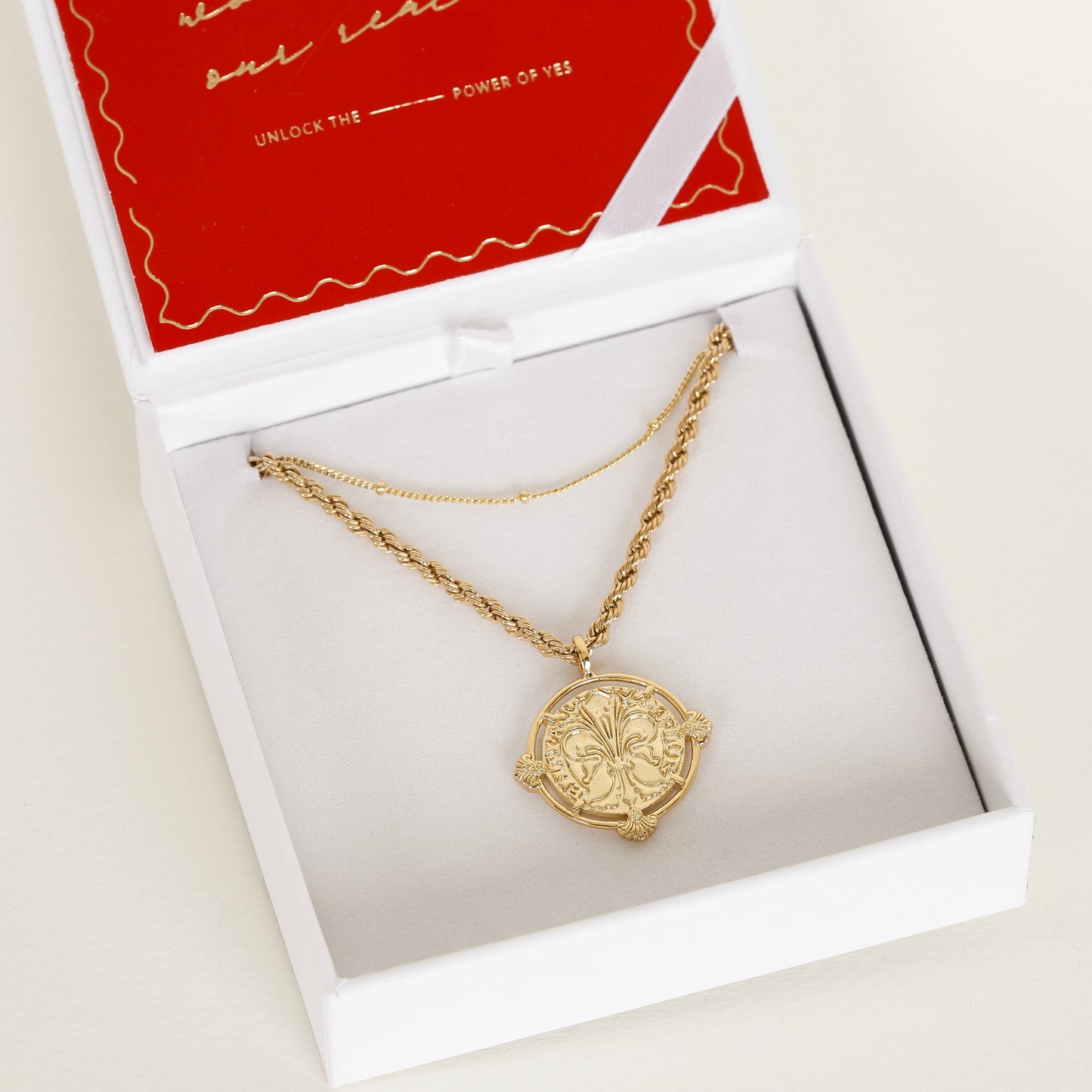 gold pendant featuring intricate patterns inspired by Palace of Versailles on gold rope chain paired with gold bobble chain in necklace box 