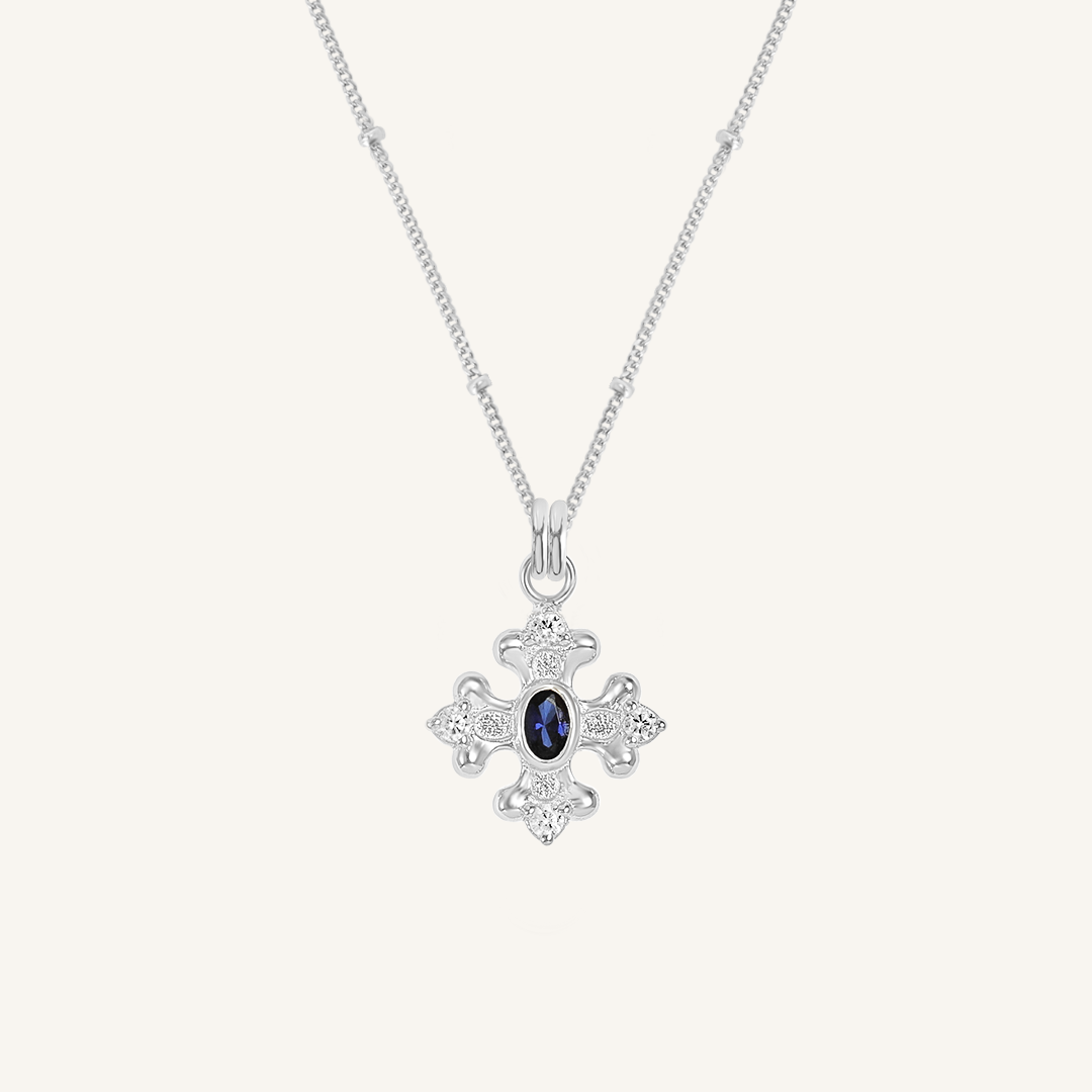 silver charm that features the intricate fleur-de-lis details found in the iconic Palace of Versailles accompanied by the deep blue stone on bobble chain on white background