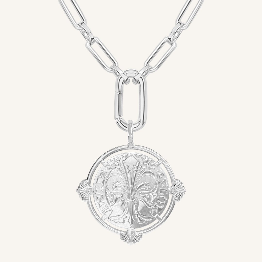 silver pendant featuring intricate patterns inspired by Palace of Versailles on silver link chain on a plain background