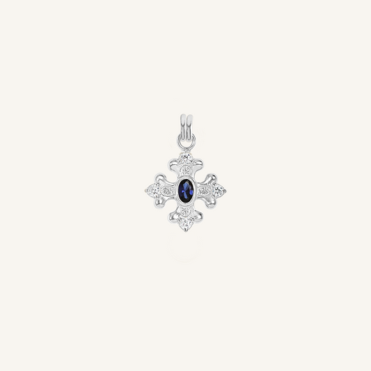 silver charm that features the intricate fleur-de-lis details found in the iconic Palace of Versailles accompanied by the deep blue stone on white background