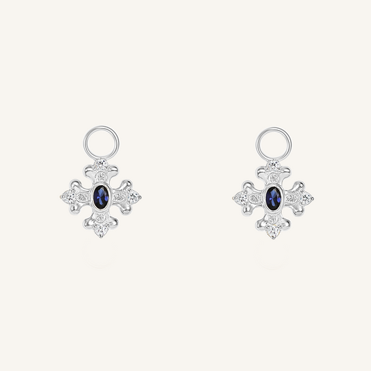 silver hoop charms that features the intricate fleur-de-lis details found in the iconic Palace of Versailles accompanied by the deep blue stone on white background