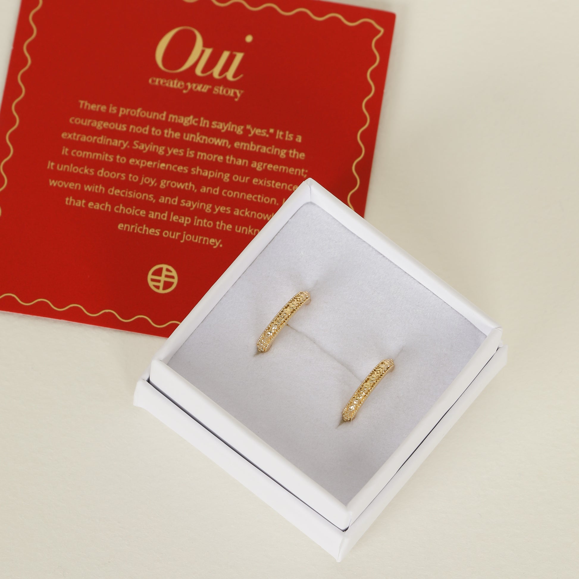 intricately designed gold hoops on white box