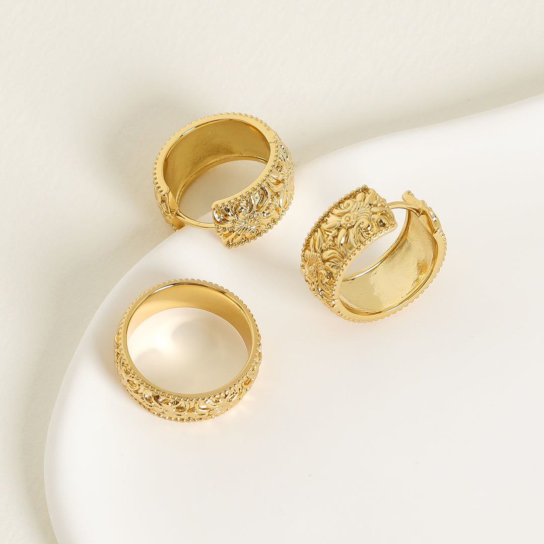 intricately designed statement gold hoops with matching ring on white background