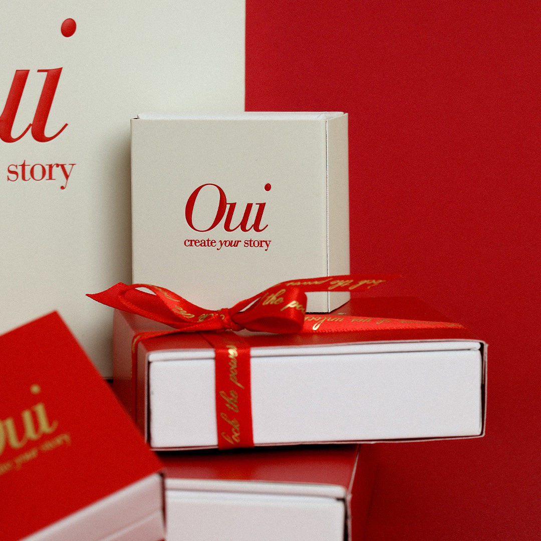 Red, gold and white gift wrapping and ribbon on red background inspired by Paris and the word Oui

