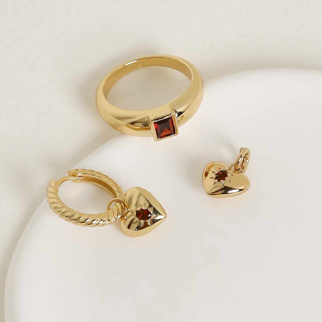 gold ring inspired by the city of love with a deep red square cubic zirconia bezel set on white background