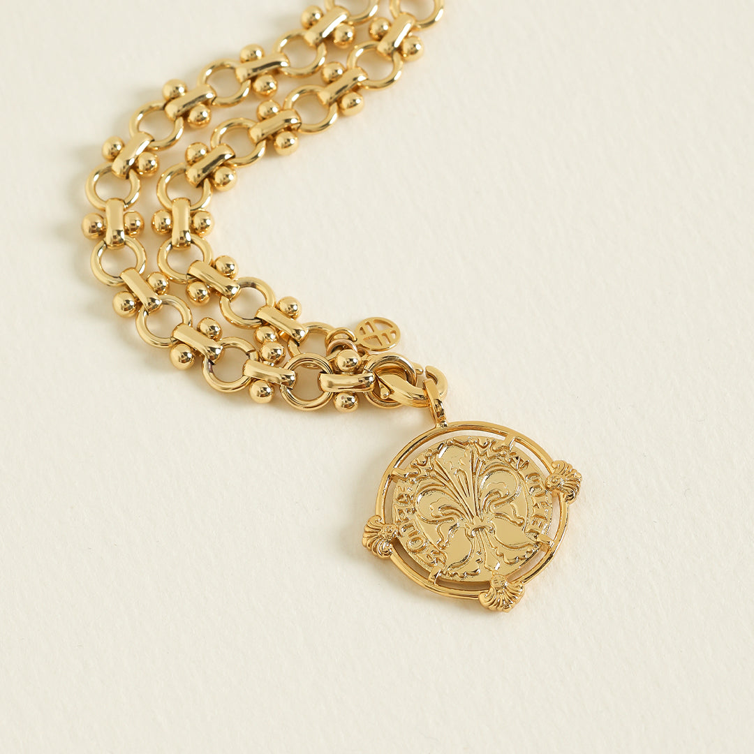 gold chain necklace inspired by Eiffel tower architecture with gold pendant featuring intricate patterns inspired by Palace of Versailles on a plain background